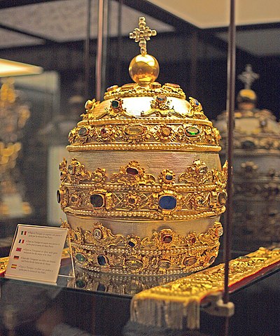 The Crown of Ba'al, also known as the Papal Tiara is a three-tiered jeweled papal crown, which is designed like a pine cone, for the priests Ba'al, the leader of the Cult of Cybele.